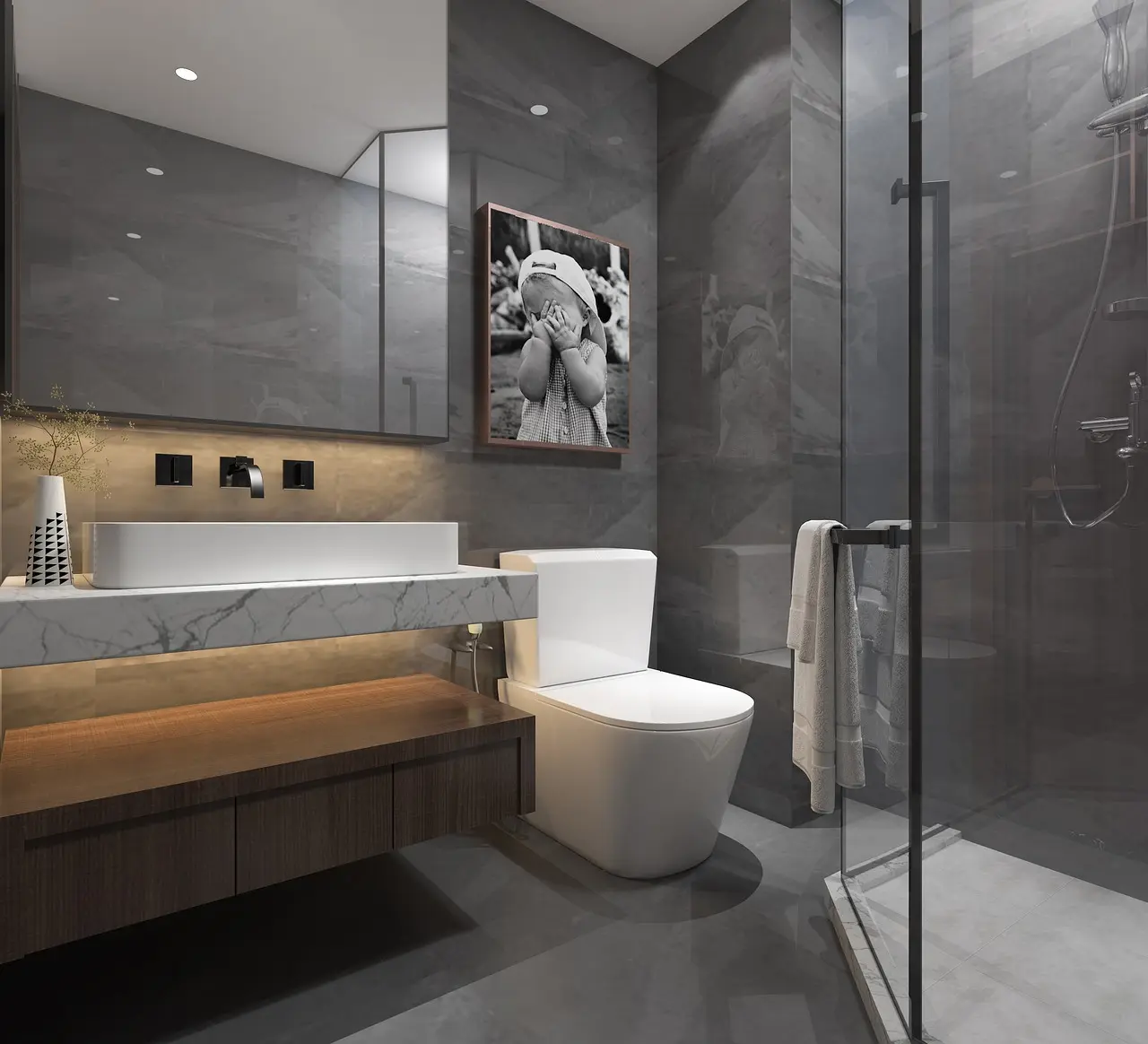 La salle de bain est moderne avec des tons gris. Sur la gauche, une grande vasque est au-dessus d'une meuble couleur bois, illuminé avec des leds blanche sous le meuble. Sur la droite, une douche à l'italienne.